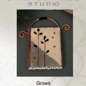 Puede incluir: Un diseño de aguja de punzón o de bordado que presenta una pequeña alfombra de color crema con un diseño marrón y gris de una planta con hojas. La alfombra está unida a un colgador de cobre con un asa negra. El diseño se titula "Grows" y es de Briar Cottage Studio.