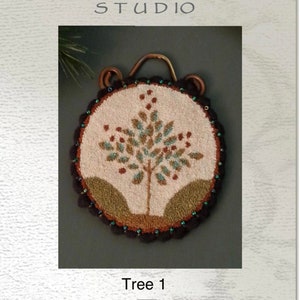 Puede incluir: Un diseño de punto de aguja o de aguja que presenta un árbol con hojas marrones, verdes y azules. El diseño está sobre un fondo blanco y está rodeado por un borde de cuentas marrones y negras. El diseño se titula "Tree 1" y es de Briar Cottage Studio.