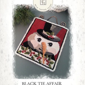 Puede incluir: Un diseño de punto de aguja de un muñeco de nieve con un sombrero de copa negro y una pajarita roja. El muñeco de nieve está rodeado de acebo verde y bayas rojas. El diseño se titula "Black Tie Affair" y es de Briar Cottage Studio.