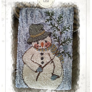 Peut inclure: Modèle de point de broderie pour un bonhomme de neige tenant une brindille, intitulé "Twiggs" et conçu par Kate Gillery. Le motif représente un bonhomme de neige blanc avec un chapeau marron, une écharpe marron et une moufle bleue.