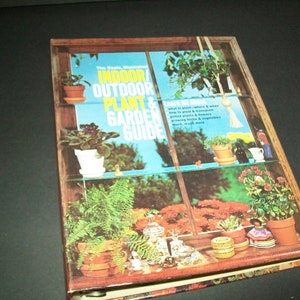 May include: The Basic Illustrated Indoor/Outdoor Plant & Garden Guide book cover features a window with a variety of potted plants, including ferns, succulents, and flowering plants. The book cover is a vibrant blue and yellow with the title in bold, black letters.