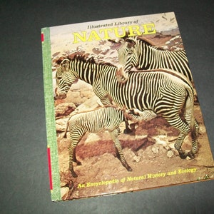 May include: A vintage book titled "Illustrated Library of NATURE" with a photo of zebras on the cover. The book's subtitle is "An Encyclopedia of Natural History and Ecology".