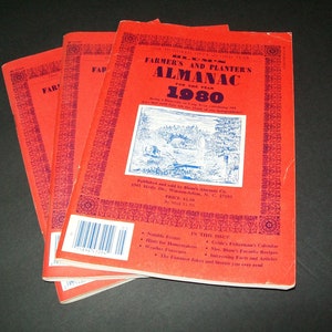 May include: A stack of four red Farmer's and Planter's Almanacs for the year 1980. The front cover features a blue illustration of a rural scene with a bridge and trees. The text "Farmer's and Planter's Almanac for the Year 1980" is printed in blue on the front cover.