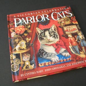 May include: A hardcover book titled "A Victorian Celebration: Parlor Cats" featuring a cat with a red bow. The cover is red with illustrations of Victorian decor and the authors' names.