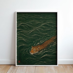 Pode incluir: Uma impressão de arte retangular emoldurada apresentando um leopardo nadando em água verde-escura com ondulações e ondas visíveis. O leopardo tem uma pelagem castanho-dourada manchada e está posicionado no canto inferior direito, com texto japonês e um selo vermelho.