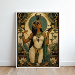 Op de afbeelding: Een ingelijste muurkunstprint met een Egyptisch geïnspireerd figuur in een witte jurk met gouden accenten, die een schorpioen vasthoudt. Het figuur draagt een schorpioen-hoofdtooi, omringd door papyrusplanten, lotusbloemen en gevleugelde godheden in goud.