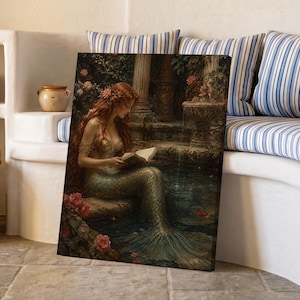 Könnte beinhalten: Ein gerahmter Kunstdruck, der eine rothaarige Meerjungfrau mit schimmerndem grünem Schwanz zeigt, die an einem steinernen Brunnen in einem Garten sitzt und ein offenes Buch liest. Die Szene zeigt dunkles Laub, rosa Blumen und klassische Steinsäulen.