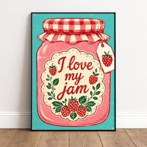 Könnte beinhalten: Ein gerahmter Wandkunstdruck mit einem rosa Glas Himbeermarmelade vor türkisfarbenem Hintergrund. Das Glas hat einen rot-weiß karierten Deckel, ein gewelltes Etikett mit dem Text I love my jam und einen kleinen Anhänger mit Himbeermotiv.