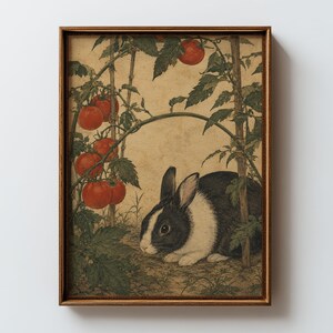 Könnte beinhalten: Ein gerahmter Kunstdruck, der ein schwarz-weißes Kaninchen in einem Gartenbeet zeigt. Das Kaninchen sitzt neben Tomatenpflanzen mit grünen Blättern und mehreren reifen roten Tomaten, die an Holzstäben vor einem hellbeigen Hintergrund hängen.