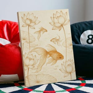 Könnte beinhalten: Ein rechteckiges Wandkunstobjekt aus Holz mit einer hellbraunen Oberfläche und einer detaillierten, braunen Lasergravur, die drei blühende Lotusblumen, große Seerosenblätter und drei Goldfische in einem Teich mit Wellen zeigt.