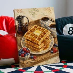 May include: A rectangular canvas print featuring a stack of golden brown waffles topped with a square of melting butter and syrup on a patterned plate. Beside the plate are two mugs of coffee, a glass syrup pitcher, and a small bowl of berries.