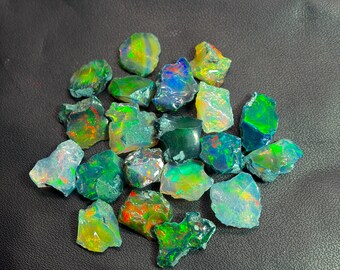 May include: A collection of raw, unpolished opal gemstones featuring a variety of irregular shapes and sizes. Each stone displays a vibrant play of color, including flashes of neon green, electric blue, fiery orange, and yellow against dark bases.