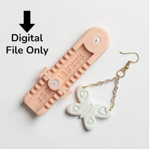 May include: A light peach-colored gauge tool with measurements and a white butterfly earring with heart details and a gold-colored hook. The text "Digital File Only" is in the upper left corner.