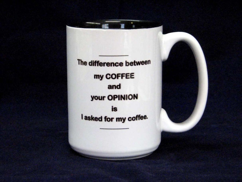 May include: White ceramic coffee mug with a black rim and handle. The mug has a humorous saying printed on it: "The difference between my coffee and your opinion is I asked for my coffee."