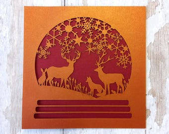 Tarjeta navideña cortada a láser: Escena de bosque con bola de nieve, tarjeta festiva hecha a mano