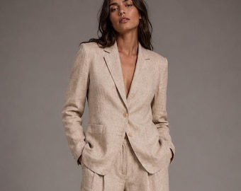 May include: A beige two-piece suit consisting of a single-breasted blazer with notched lapels and two front buttons, paired with high-waisted, wide-leg trousers. The set features a textured fabric finish and a relaxed, tailored silhouette.