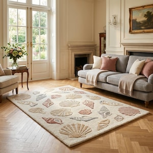 Puede incluir: Una alfombra rectangular con fondo color crema y un patrón repetitivo de diversas conchas marinas en tonos bronceado, marrón claro, rosa suave y azul apagado. La alfombra tiene una superficie texturizada y con mechones de formas definidas.