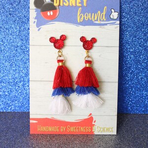 May include: Red, white, and blue tassel earrings with a red glitter Mickey Mouse head charm. The earrings are displayed on a card that says "DISNEY bound" and "HANDMADE BY SWEETNESS & SCIENCE".