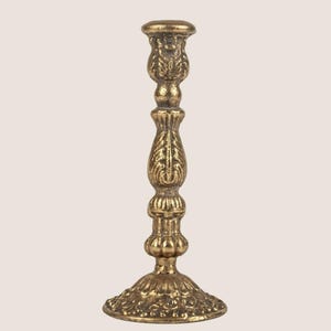 May include: A gold-colored candlestick with an ornate, detailed design. The candlestick features a round base, a slender stem, and a cup-shaped top. The surface has a textured, antique appearance, suggesting a vintage or classic style.