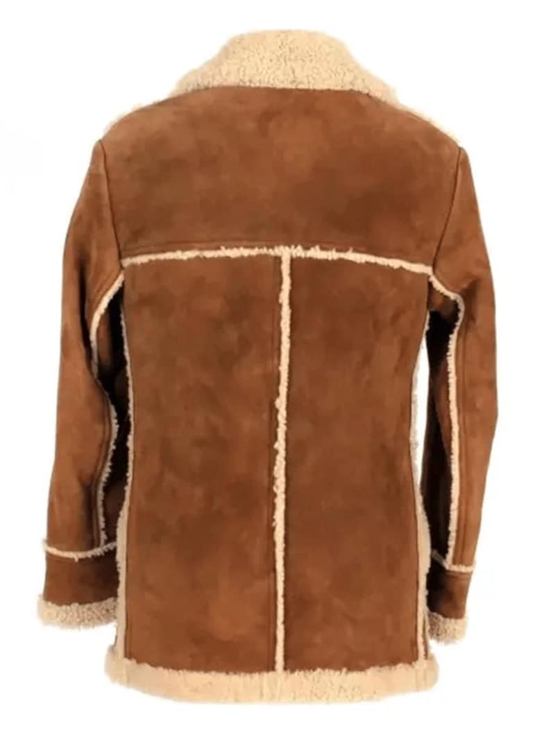 May include: A brown suede jacket with a cream-colored shearling lining and trim. The jacket features a classic design with a notched collar, long sleeves, and a button-up front. The back of the jacket is visible, showcasing the seams and the texture of the suede.