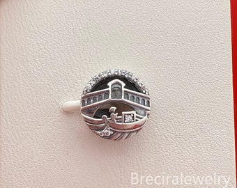 May include: A silver-toned charm with a Venetian theme. The charm features a bridge, a gondola with passengers, and a sparkling halo of clear stones. The charm is round and has intricate details.