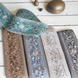 Può includere: Un assortimento di nastri decorativi ricamati in vari colori, tra cui verde acqua, marrone, blu e grigio. Ogni nastro presenta motivi floreali e dettagli intricati, adatti per lavori artigianali e abbellimenti.