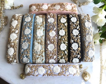 May include: Assortment of eight embroidered trim ribbons in various colors, including light blue, white, gold, and black. The trim features a delicate floral design with white flowers and gold accents.