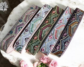 May include: Five different embroidered trim ribbons in shades of pink, blue, green, and purple. Each ribbon features a geometric pattern with floral and leaf motifs.