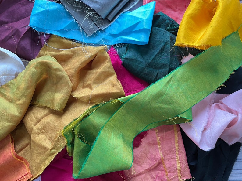 May include: A collection of fabric scraps in various colors, including yellow, green, blue, pink, and red. The fabric scraps are arranged in a random pattern and have a variety of textures.