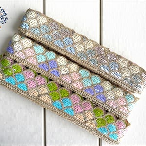 Könnte beinhalten: Drei dekorative Zierleisten mit einem schuppenartigen Muster in Blau-, Grün-, Rosa- und Beigetönen. Die Zierleisten haben einen beigen Rand und sind diagonal auf einer weißen Oberfläche angeordnet. Das Boho Tree-Logo befindet sich oben links.