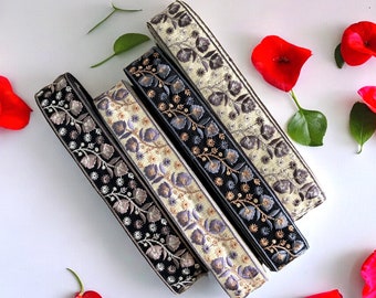 May include: Four different trims of embroidered ribbon with floral designs. The ribbons are in shades of black, cream, and gray.