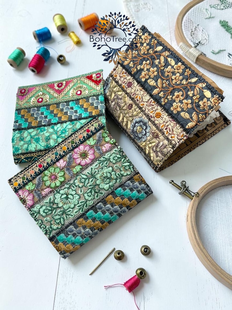 K&ouml;nnte beinhalten: Zwei quadratische Stoffnotizb&uuml;cher mit komplexen, mehrfarbigen floralen und geometrischen Stickmustern. Ein Notizbuch zeigt leuchtend gr&uuml;ne und rosa Blumenmotive, das andere goldene und schwarze Blumenstickereien. Enth&auml;lt den Text BohoTree.com.