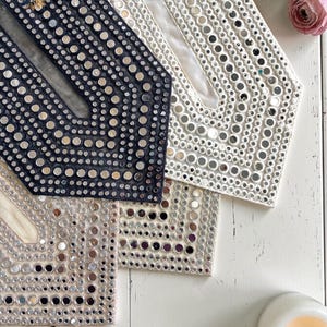 May include: A white ceramic mug with a black handle and the text "But First, Coffee" in a black, handwritten-style font. The mug is on a white surface.