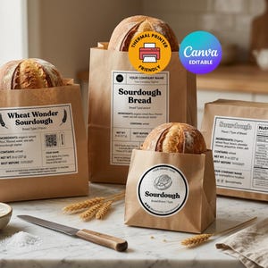 May include: Four brown paper bags containing round loaves of sourdough bread, each featuring white rectangular or circular labels with black text, ingredient lists, and nutrition facts. A small bowl of flour, salt, and a knife are on the table.
