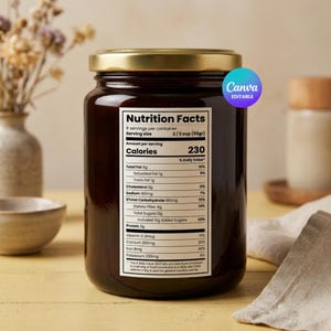 May include: A glass jar with a gold lid filled with a dark brown substance. The jar has a nutrition facts label with details on calories, fat, and other nutritional information. The label is white with black text. The jar is on a light yellow surface.