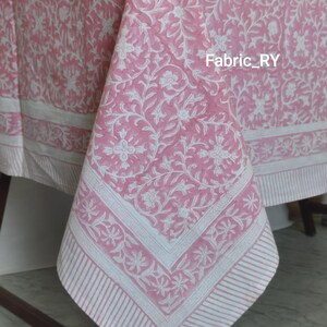 May include: A pink and white floral tablecloth with a detailed pattern. The tablecloth has a white border with a striped design. The text "Fabric_RY" is visible on the tablecloth.