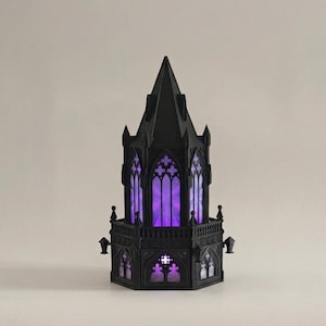 Könnte beinhalten: Ein schwarzer Turm im gotischen Stil mit aufwendigen architektonischen Details, darunter Spitzbogenfenster und ein spitzes Dach. Die Fenster leuchten mit einem leuchtenden violetten Licht und bilden einen auffälligen Kontrast zur dunklen Struktur. Der Turm hat einen Balkon.