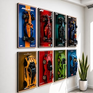May include: A series of framed Formula 1 car models. The artworks feature a variety of car designs in colours like blue, orange, red, green, and black. Each frame displays the car's brand and model, including McLaren and Ferrari.