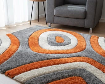 May include: A gray, orange, and white patterned area rug with a shaggy texture. The rug features a circular design with concentric rings of orange, white, and gray. The rug is placed on a wooden floor.