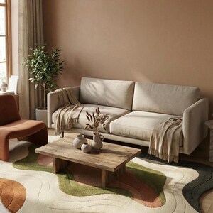 May include: A living room scene featuring a beige sofa with a fringed throw, a wooden coffee table, and a colorful rug with an abstract wave design. The room has a warm, inviting atmosphere with neutral tones and natural light.
