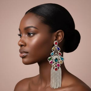 May include: A glamorous, dangling earring featuring a cascade of colorful gemstones and a fringe of shimmering silver chains. The earring showcases a vibrant array of red, blue, green, and pink stones, creating a dazzling effect. The earring is a statement piece.