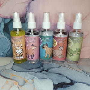 May include: Five clear spray bottles with white spray nozzles. Each bottle has a colorful label with a cartoon animal and the words "Fursuit Spray". The animals include a tiger, fox, dog, cat, and lizard.