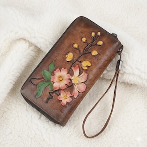 Carteira feminina artesanal em couro genuíno curtido vegetal, estilo vintage, com alça de pulso com relevo floral e elegância rústica.