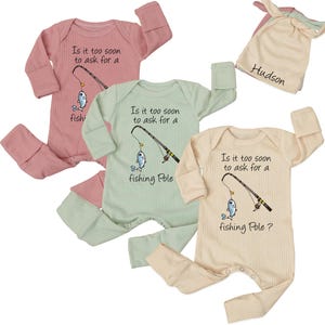 May include: Three baby rompers in pink, green, and cream colors, each with a ribbed texture. The front of each romper features a fishing pole graphic and the text "Is it too soon to ask for a fishing Pole?" A matching cream-colored hat is also included.