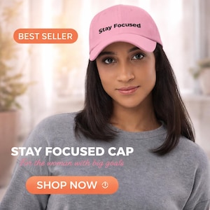 Peut inclure: Casquette de baseball rose avec l'inscription "Stay Focused" en noir. L'image comprend également le texte "Best Seller", "Stay Focused Cap" et "Shop Now". La casquette est portée par une personne portant un sweat-shirt gris.