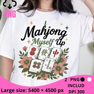Peut inclure: Un t-shirt blanc avec un motif graphique portant l'inscription "I Mahjong Myself Up" en lettres noires et vertes. Le design comprend cinq tuiles de mah-jong entourées de fleurs roses et de feuilles vertes, agrémentées de petites étoiles jaunes et vertes.