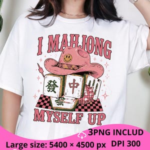 Peut inclure: Un t-shirt blanc avec une impression graphique portant le texte I MAHJONG MYSELF UP en lettres roses. Le motif comprend un chapeau de cowboy rose avec un visage souriant, plusieurs tuiles de mah-jong avec des caractères chinois et une boule à facettes.