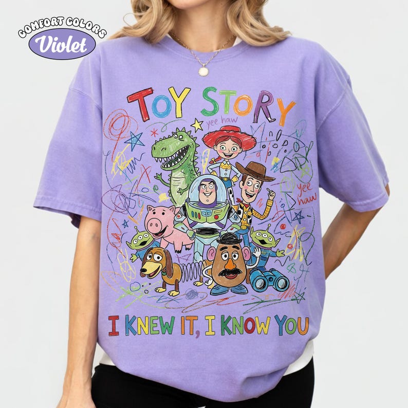 Puede incluir: Una camiseta violeta de manga corta con un gr&aacute;fico colorido de personajes de Toy Story como Woody, Buzz Lightyear, Jessie, Rex, Hamm, Slinky Dog, Mr. Potato Head y Aliens, con dibujos de garabatos y el texto TOY STORY I KNEW IT, I KNOW YOU.