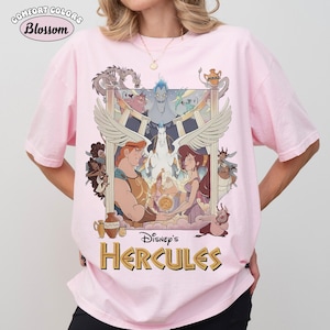 May include: Pink Comfort Colors t-shirt featuring a graphic from Disney's Hercules. The design includes Hercules, Megara, and other characters, with the text "Disney's Hercules" in gold. The shirt also has the text "Blossom" in a circle.