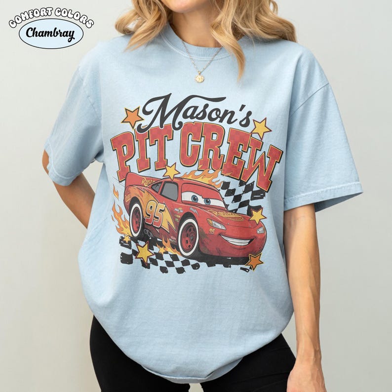 May include: Light blue t-shirt with the text "Mason's Pit Crew" and a graphic of the character Lightning McQueen from the movie Cars. The graphic includes flames, stars, and a checkered flag design.